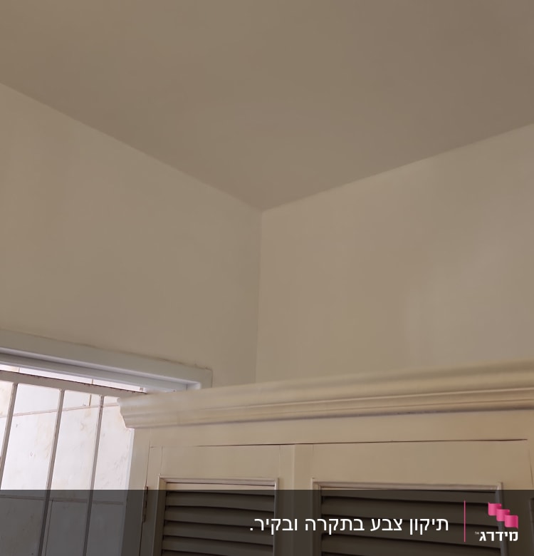 ארון עץ עם דלתות תריס ליד חלון עם סורגים